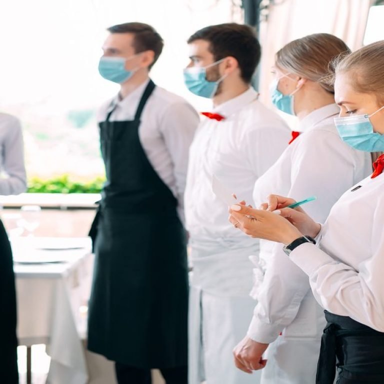 Employees of a Restaurant or Hotel in protective masks. End Of Quarantine. Restaurant Manager and his staff on the terrace. interaction with the chef in the restaurant